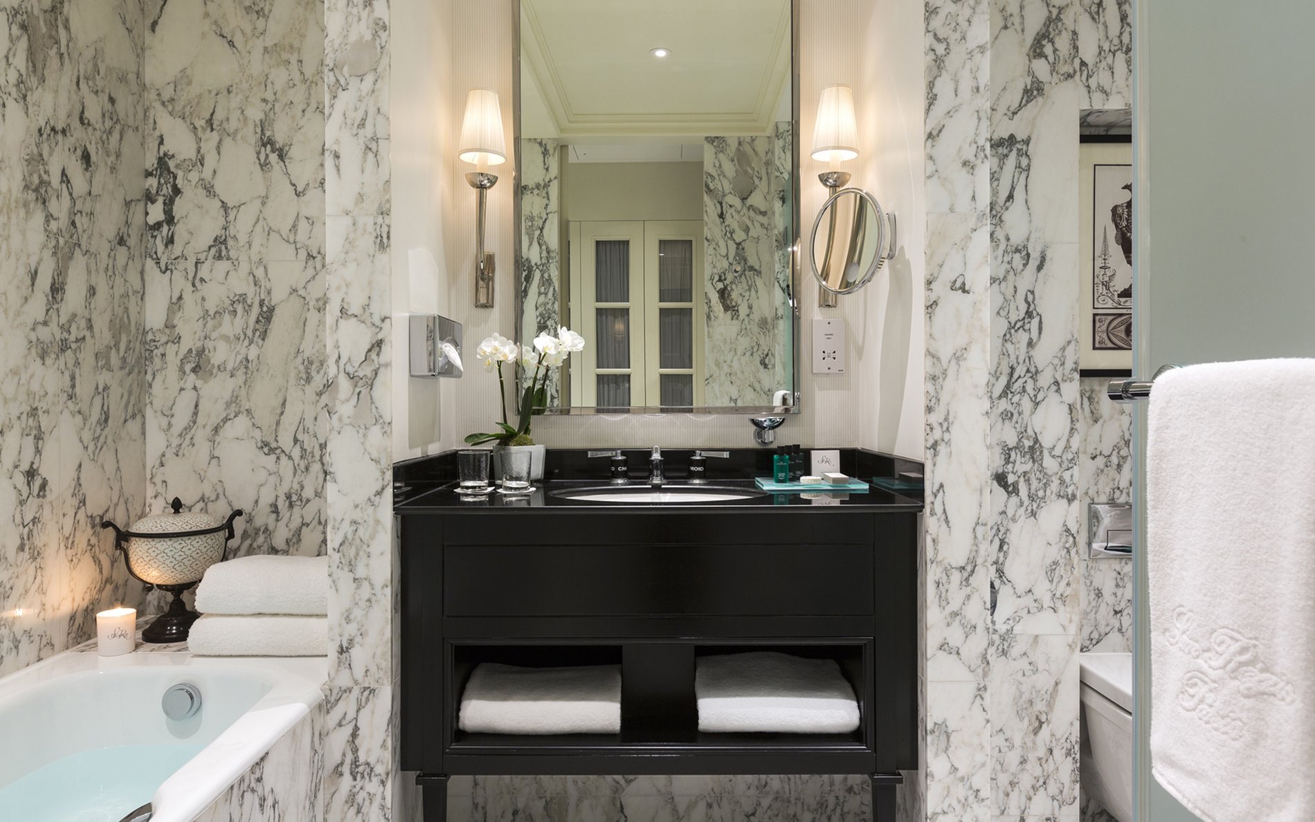 Salle de bain classique de l’Hôtel San Régis à Paris, décor en marbre blanc et noir avec double vasque élégante.